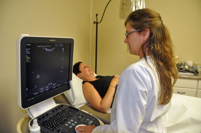 Pregnancy Health Center Nurse Manager Brenda Droege demonstrates an ultrasound on PHC Executive Director Heather Mitchell in the center&#039;s new medical clinic.